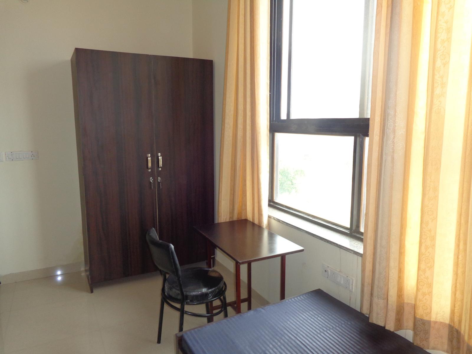 Spacious furnished PG room with study table and wardrobe